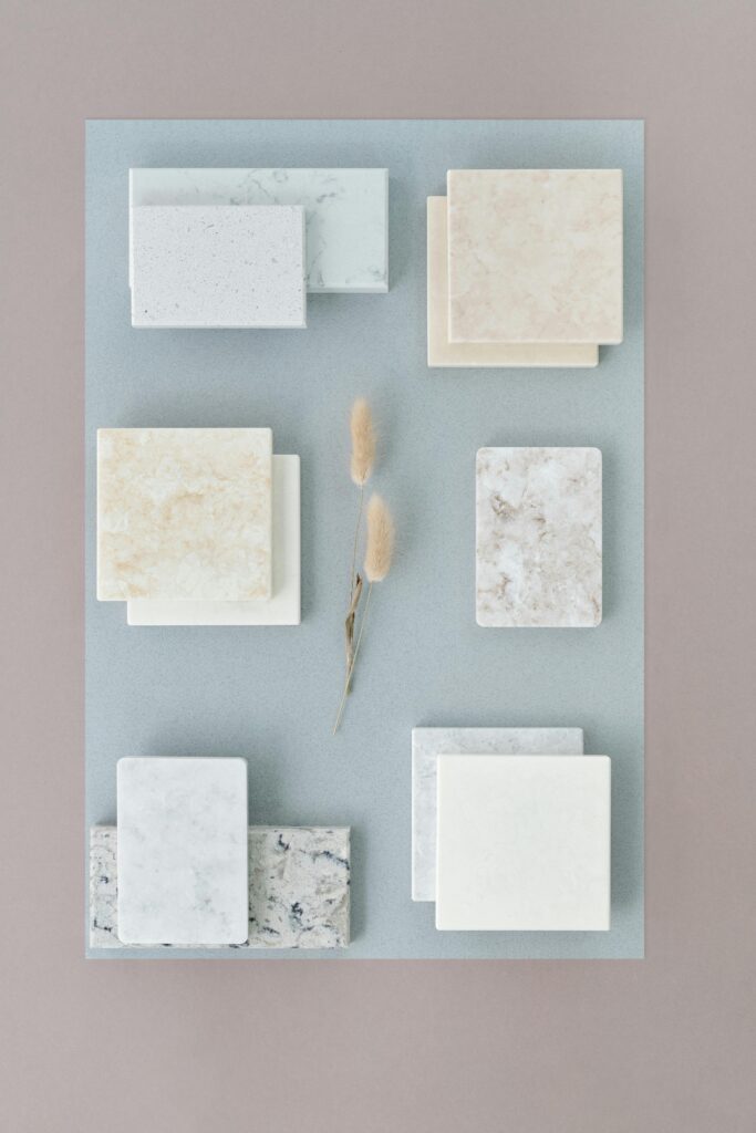 Aesthetic flat lay of stone tile samples and dried flowers on a neutral surface for interior design concepts.