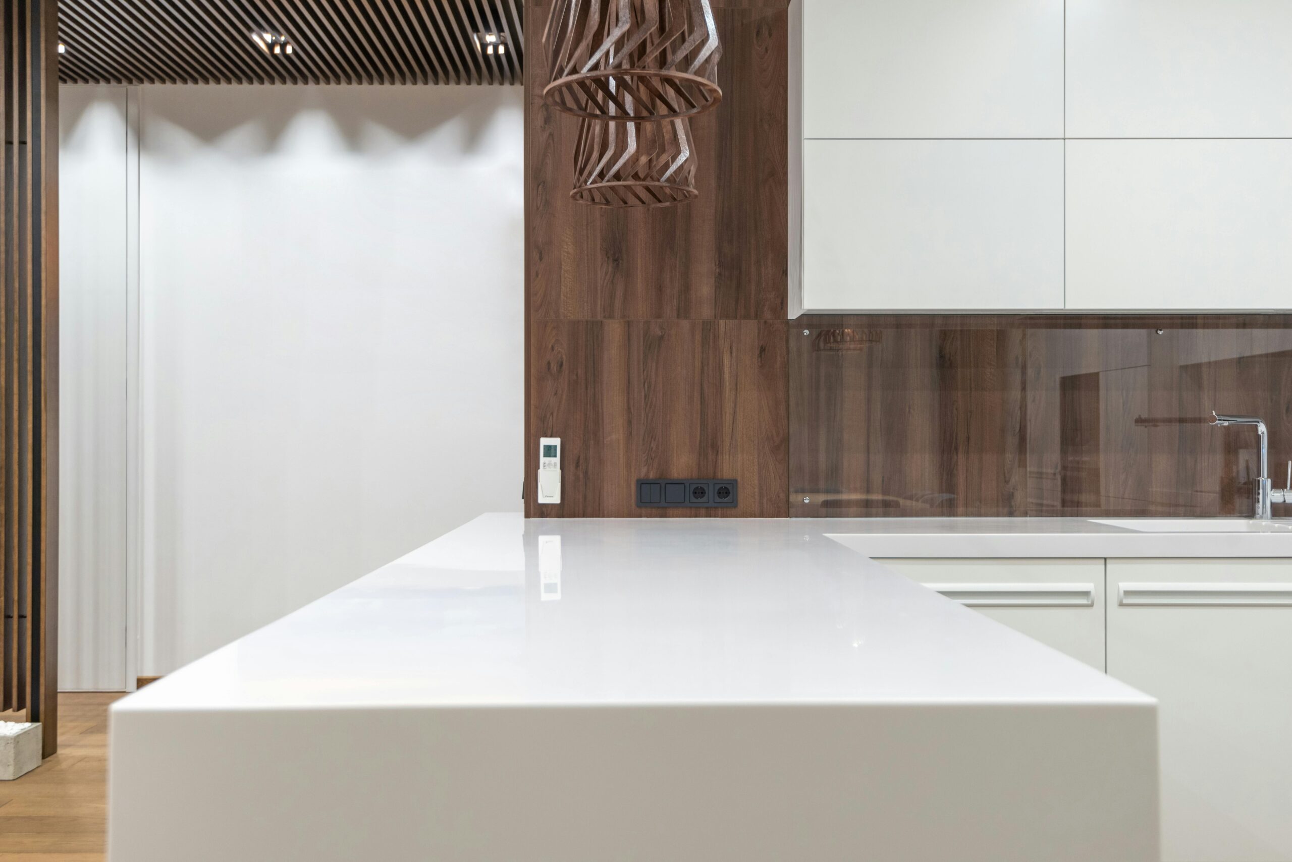 Clean empty kitchen counter with sink and cupboards on wooden wall located in spacious apartment with stylish design at home