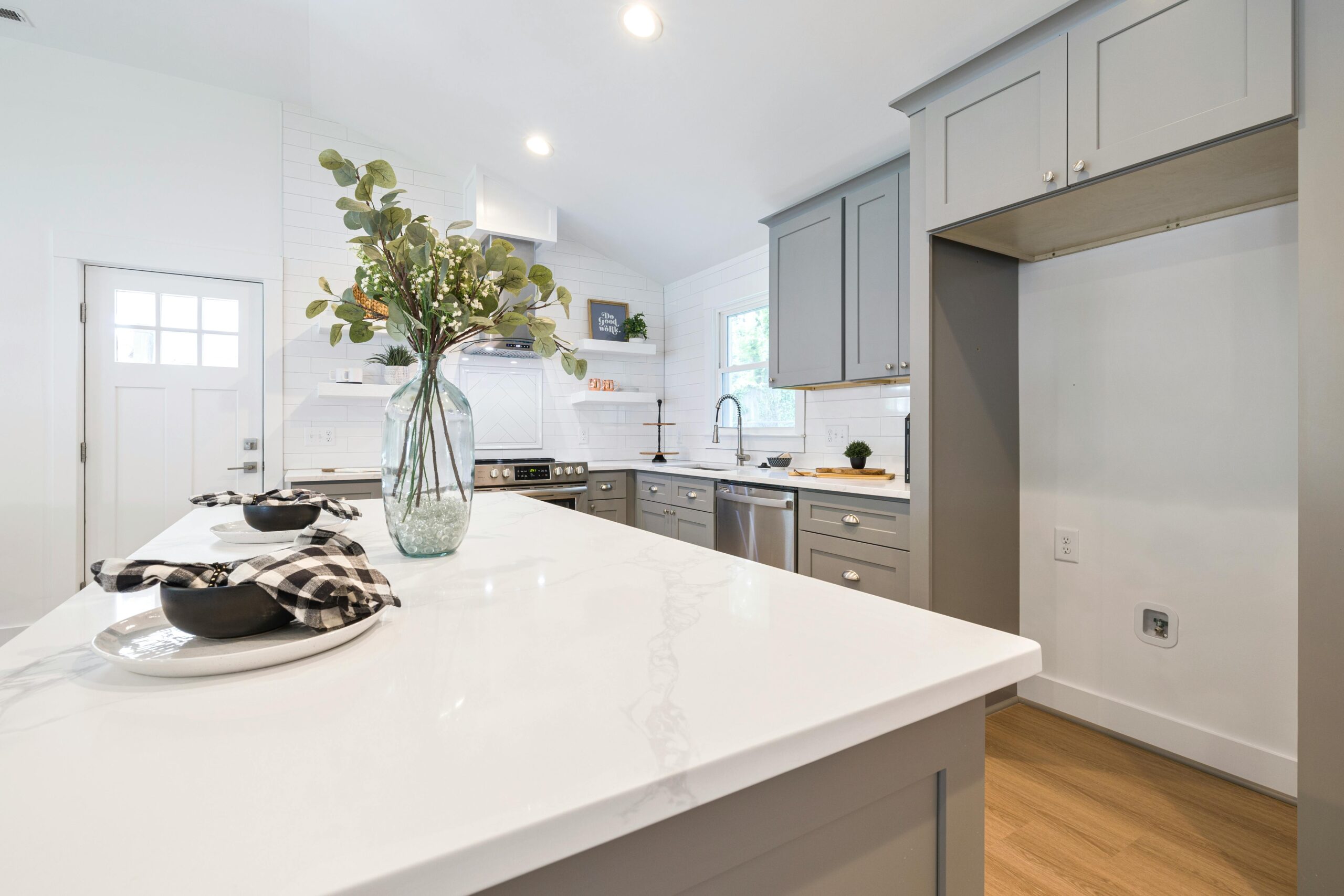 Elegant modern kitchen featuring minimalist cabinets, marble countertop, and decorative vase with eucalyptus.