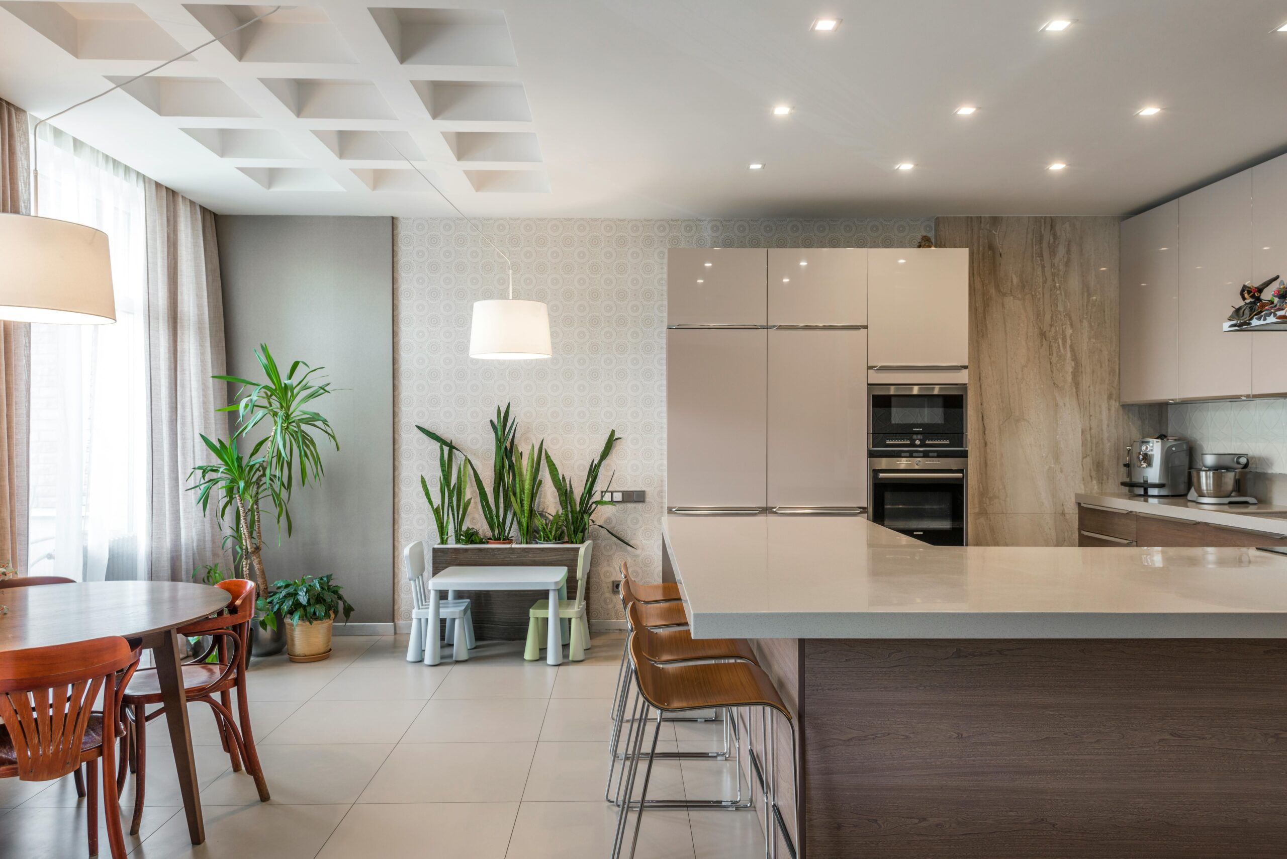 Spacious kitchen with elegant furnishings and greenery, perfect for modern living.